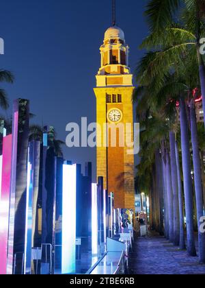 Blick auf den alten Kowloon Bahnhof Uhrenturm in Hongkong bei Nacht mit einer farbenfrohen Lichteranzeige Stockfoto