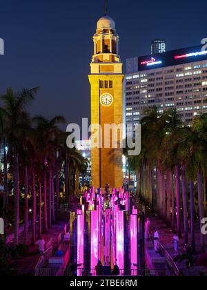 Blick auf den alten Kowloon Bahnhof Uhrenturm in Hongkong bei Nacht mit einer farbenfrohen Lichteranzeige Stockfoto