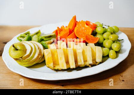 Verschiedene frische Fruchtscheiben, die ordentlich auf einer weißen Platte präsentiert werden, ideal für einen gesunden Snack oder ein Dessert. Stockfoto