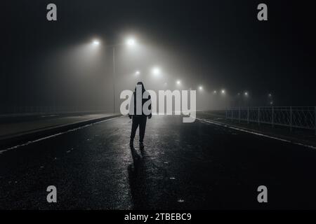 Trauriger Mann allein, der die Gasse entlang läuft, auf der nebligen Straße Stockfoto