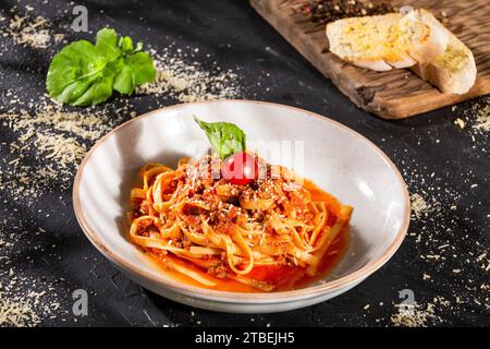 Köstliche Pasta in Bolognesesauce, mit Tomaten und grünem Basilikumblatt Stockfoto