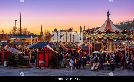 Zürich, Schweiz - 23. November 2023: Weihnachtsmarkt vor der Oper am Sechselautenplatz-Bellevue in Zürich bei Sonnenuntergang Stockfoto
