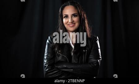 Junge selbstbewusste Frau in einer schwarzen Studioumgebung Stockfoto