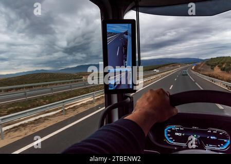 Blick von der Fahrposition eines Lkws auf eine Straße mit Gewitterwolken darüber. Stockfoto