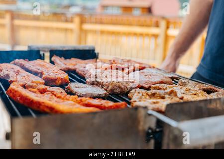 BBQ Picknick draußen. Gegrillter Schweinebauch. Fleisch dreht sich auf dem Grill. Appetitliches gebratenes Schweinefleisch. BBQ und Grill. Gegrilltes Fleisch. Picknick im Freien mit gegrilltem Grill Stockfoto