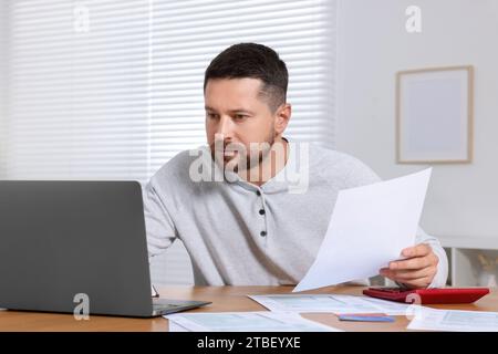 Mann, der Steuern am Tisch im Zimmer macht Stockfoto