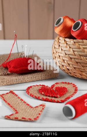 Sackleinen, Garnspulen, Kissen und Nadeln auf weißem Holztisch Stockfoto