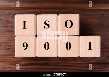 Würfel mit Abkürzung ISO und Nummer 9001 auf Holztisch, flach gelegt Stockfoto