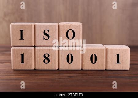 Würfel mit der Abkürzung ISO und der Nummer 18001 auf Holztisch Stockfoto
