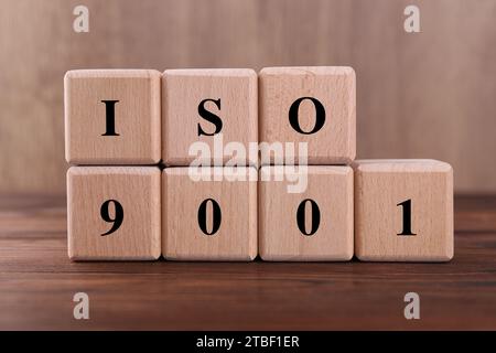 Würfel mit der Abkürzung ISO und der Nummer 9001 auf Holztisch Stockfoto