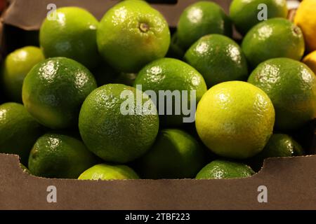 Viele frische grüne Limetten auf dem Container auf dem Markt, Nahaufnahme Stockfoto