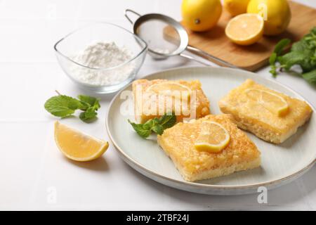 Leckere Zitronenriegel und Minzbonbons auf weißem Tisch Stockfoto