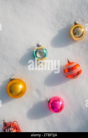 Farbenfrohe weihnachtsbaumschmuck aus Vintage-Glas in Pastellfarben, die im Schnee liegen Stockfoto