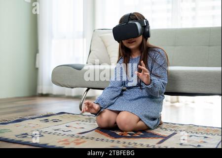 Ein süßes und aufgeregtes junges asiatisches Mädchen trägt ein VR-Headset und erlebt zu Hause ein Virtual-Reality-Spiel. Virtual-Reality-Gaming Stockfoto