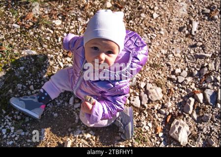 Porträt eines kleinen Mädchens, das auf einem Boden in der Natur sitzt Stockfoto