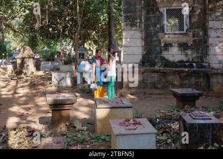 Zwei indische Frauen, die sich zwischen den Gräbern von Sadhus oder heiligen Männern der (Hindu-)Goswami-Schule unterhalten; in Dashnami Goswami Akhara, Mumbai, Indien Stockfoto