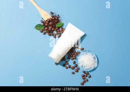 Nahaufnahme einer Kosmetikröhre mit Meersalz und Kaffeebohnen auf blauem Hintergrund. Kaffee gilt als eine der natürlichen Zutaten Stockfoto