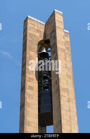 Eine nahe Aufwärtsaufnahme der beiden Steinpfeiler von Deeds Carillon zeigt den Stapel dunkler Glocken, die zwischen ihnen gegen einen hellblauen Himmel in Dayton, Ohio, hängen. Stockfoto