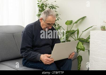 Vielbeschäftigter, kluger, reifer, professioneller Mann, der mit einem Laptop sitzt Mittelalter erwachsener Geschäftsmann, leitender Unternehmer mit Fernarbeit im mittleren Alter oder Stockfoto