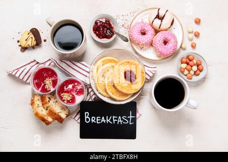 Tisch mit verschiedenen amerikanischen Keksen, Donuts, Pfannkuchen und Kaffeetassen auf weißem Hintergrund. Draufsicht. Stockfoto