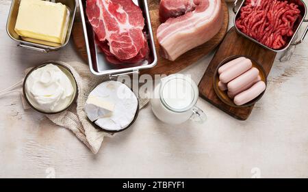 Gesättigte Fette auf Tischen. Rohes Fleisch, Würstchen, Käse, Butter. Schlechtes Essenskonzept. Draufsicht, Kopierraum. Stockfoto