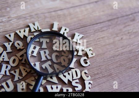 Lupe mit verstreuten Buchstaben auf dem Tisch. Kopierbereich für Text. Bildungskonzept. Stockfoto