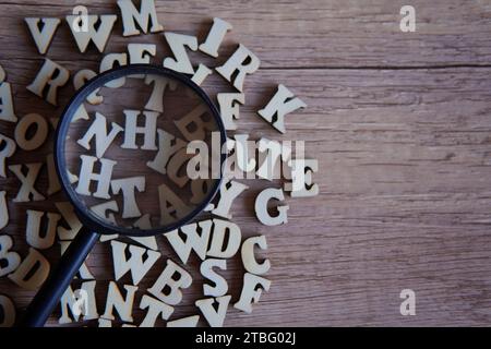 Lupe mit verstreuten Buchstaben auf dem Tisch. Kopierbereich für Text. Bildungskonzept. Stockfoto