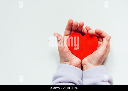 Ein rotes Herz in der Hand eines Kindes Stockfoto