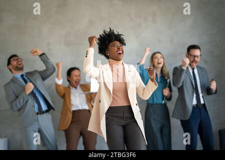 Das Team ist begeistert von verschiedenen Geschäftsleuten und feiert gemeinsam im Büro den Unternehmenssieg Stockfoto