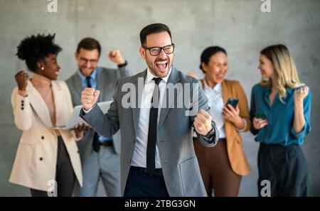 Das Team ist begeistert von verschiedenen Geschäftsleuten und feiert gemeinsam im Büro den Unternehmenssieg Stockfoto