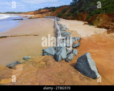 Aus der Vogelperspektive sehen Sie Felsen um eine Reihe verwitterter Pylonen hoch an einem Sandstrand am Point Roadknight an der Great Ocean Road in Victoria, Australien Stockfoto