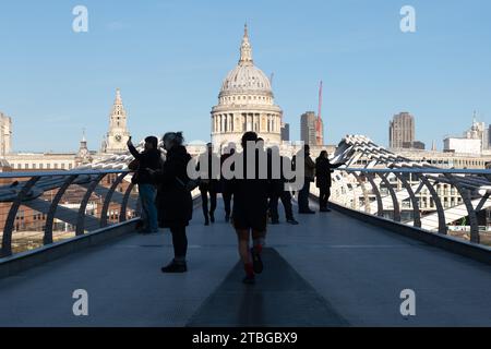 Silhouetten von Menschen auf der Millennium Bridge, London, Großbritannien, mit der St. Paul's Cathedral hell von der Sonne im Hintergrund beleuchtet Stockfoto