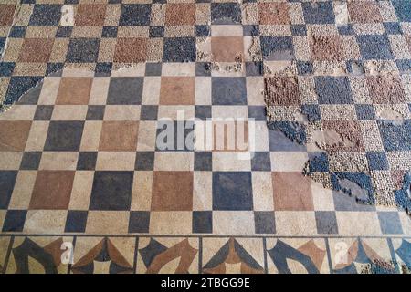 Archäologische Überreste von Boden bemalt mit farbigen quadratischen Figuren und darüber restaurierte Reste von römischem Mosaik mit geometrischen Figuren, rot und blau quadratisch Stockfoto