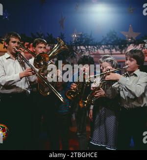 1, 2 oder 3, ZDF Quizshow für Kinder, Deutschland, 1983, im Bild: Moderator Michael Schanze mit der Jugend-Bläsergruppe Strande. 1, 2 oder 3, TV-Quiz-Show für Kinder, Deutschland, 1983, Bild: Moderator Michael Schanze mit der Jugendbläsergruppe Strande. Stockfoto