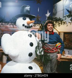 1, 2 oder 3, ZDF Quizshow für Kinder, Deutschland, 1983, im Bild: Moderator Michael Schanze mit einem Schneemann. 1, 2 oder 3, TV-Quizshow für Kinder, Deutschland, 1983, Bild: Moderator Michael Schanze mit einem Schneemann Stockfoto