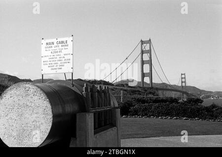 Blick auf die Golden Gate Bridge, im Vordergrund ein Durchschnitt durch ein Beispiel der Hauptseile mit einer Infotafel zu den beinhalteten Baumaterialien, der Gesamtlänge und dem Gewicht der Trägerkabel, San Francisco 1962. Blick auf die Golden Gate Bridge, im Vordergrund ein Abschnitt durch ein Beispiel der Hauptkabel mit einer Informationstafel über die verwendeten Baumaterialien, Gesamtlänge und Gewicht der Trägerkabel, San Francisco 1962. Stockfoto