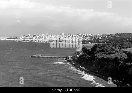 Blick von der Golden Gate Bridge auf die Skyline von San Francisco, rechts die Küstenstraße Long Avenue sowie mittig der Steg Torpedo Wharf, der ein beliebtes Ziel für Touristen und Angler darstellt, 1962. Blick auf die Skyline von San Francisco von der Golden Gate Bridge, mit Long Avenue auf der rechten Seite und Torpedo Wharf, ein beliebtes Ziel für Touristen und Angler, im Zentrum, 1962. Stockfoto