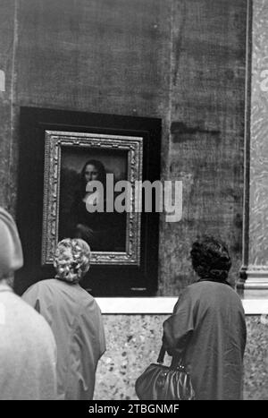 Museumsbesucherinnen im Louvre betrachten die Mona Lisa, Paris 1965. Museumsbesucher im Louvre mit Blick auf die Mona Lisa, Paris 1965. Stockfoto