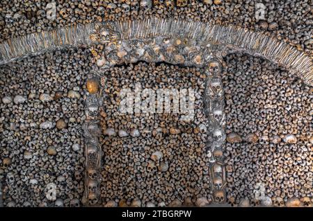 Mauer aus menschlichen Knochen und Schädeln, die makabre Designs in der Kapelle der Knochen in der Stadt Evora in Portugal schaffen. Stockfoto