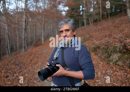 Geringe Tiefe des Feldes Porträt eines Landschaftsfotografen mittleren Alters, der im Wald die Kamera hält Stockfoto