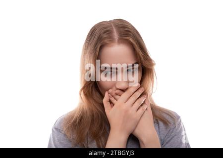 Porträt eines verwirrten Teenagermädchens mit blonden Haaren in einem grauen T-Shirt auf weißem Hintergrund Stockfoto