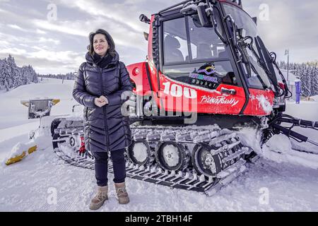 Reit Im Winkl, Deutschland. Dezember 2023. Bayerns Landwirtschaftsministerin Michaela Kaniber (CSU) steht bei der Eröffnung der Ski- und Wintersaison auf der Skipiste Winklmoos-Alm vor einem Pistenfahrer. Das Skigebiet auf rund 1200 Metern nimmt seinen Skibetrieb am 09.12.2023 auf. Quelle: Uwe Lein/dpa/Alamy Live News Stockfoto