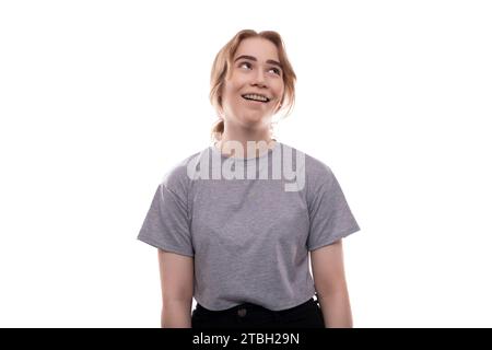 Wunderschönes blondes Teenager-Mädchen in einem grauen T-Shirt vor Studiohintergrund Stockfoto