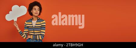 Ansprechende afroamerikanerin in Stadtkleidung mit einer Denkblase auf orangem Hintergrund, Banner Stockfoto