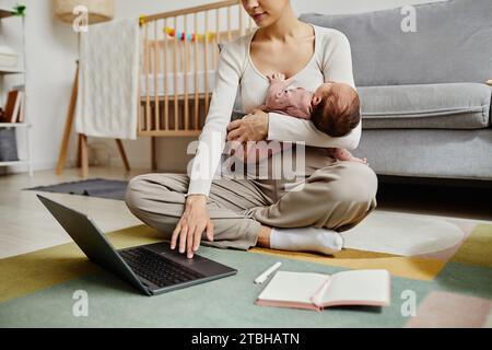 Frau, die auf dem Boden sitzt und das Baby hält Stockfoto
