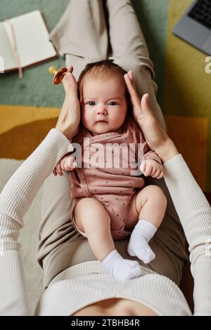 Süßes Baby, das auf Mom Knien liegt Stockfoto