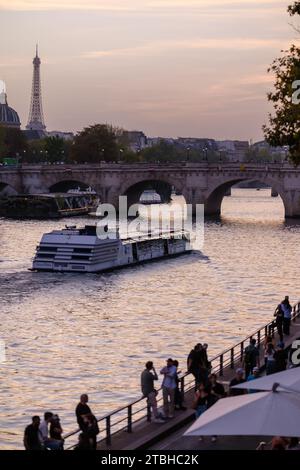 Paris, Frankreich - 8. Oktober 2023 : Blick auf Menschen, die an der seine spazieren gehen, ein Touristenboot und den Eiffelturm im Hintergrund in Paris Fra Stockfoto