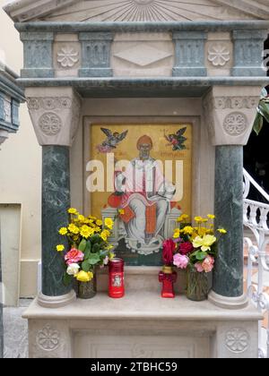 Korfu Stadt, Griechenland. Mai 2022. Blumen und Kerzen stehen vor einem Bild von St. Spiridon vor der griechisch-orthodoxen Kirche Agios Spiridon, die dem schutzheiligen der Insel gewidmet ist, in Korfu-Stadt auf der Ionischen Insel Korfu in Griechenland. Quelle: Beate Schleep/dpa/Alamy Live News Stockfoto