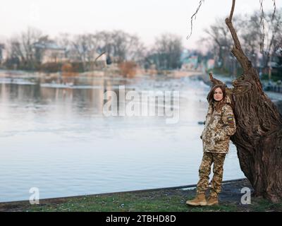 Ukrainische Soldatinnen, die während des Urlaubs in der Nähe des Sees im Park ruhen. Frauen und Krieg in der Ukraine. Russische militärische Invasion. Übersetzung aus dem Ukrainischen: AR Stockfoto