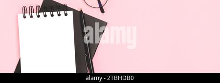 Banner mit Notizblock-Mock und Schreibwaren auf rosafarbenem Hintergrund. Komposition mit Platz für Text. Stockfoto